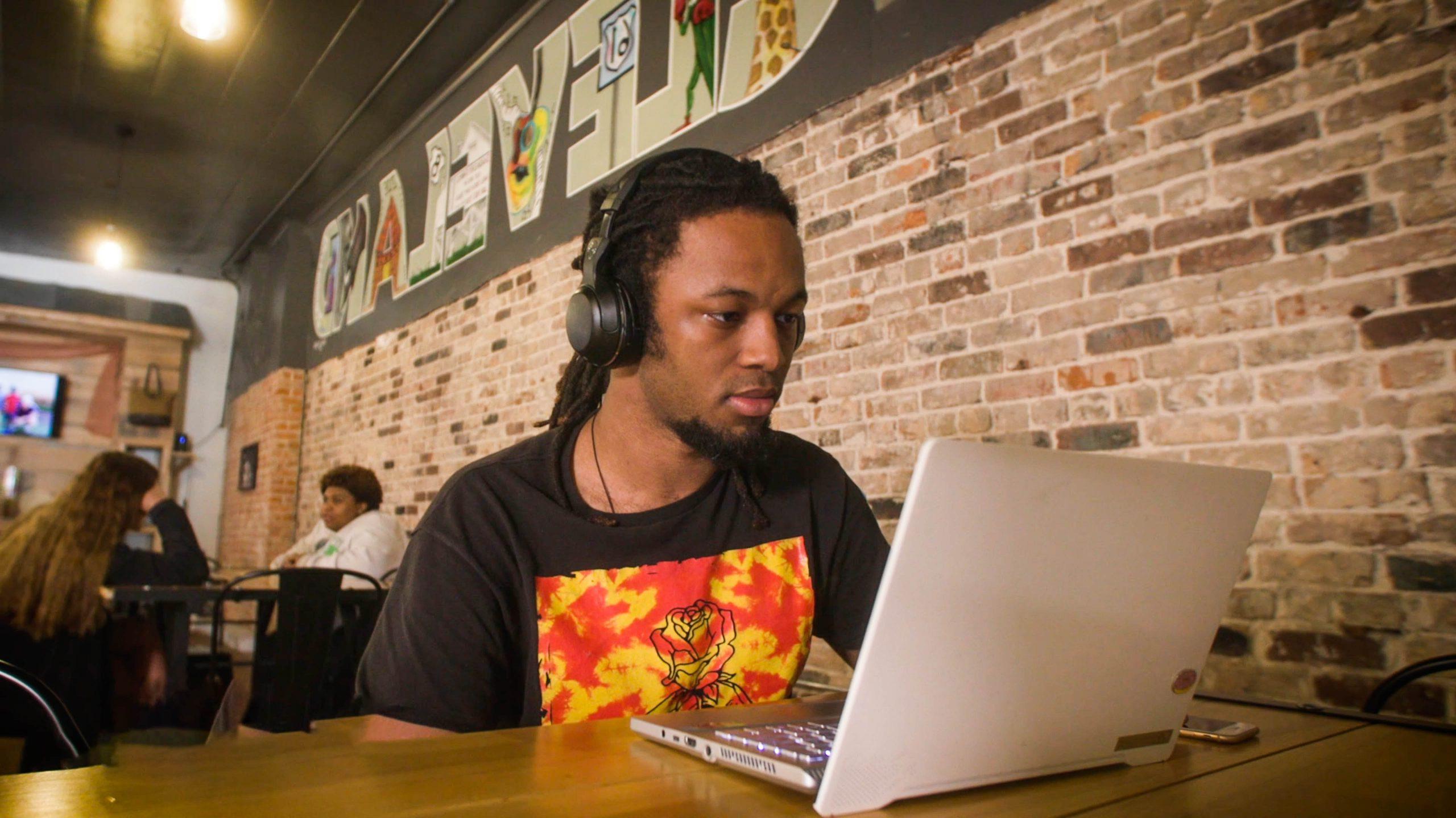 Student at coffee shop doing homework on laptop.